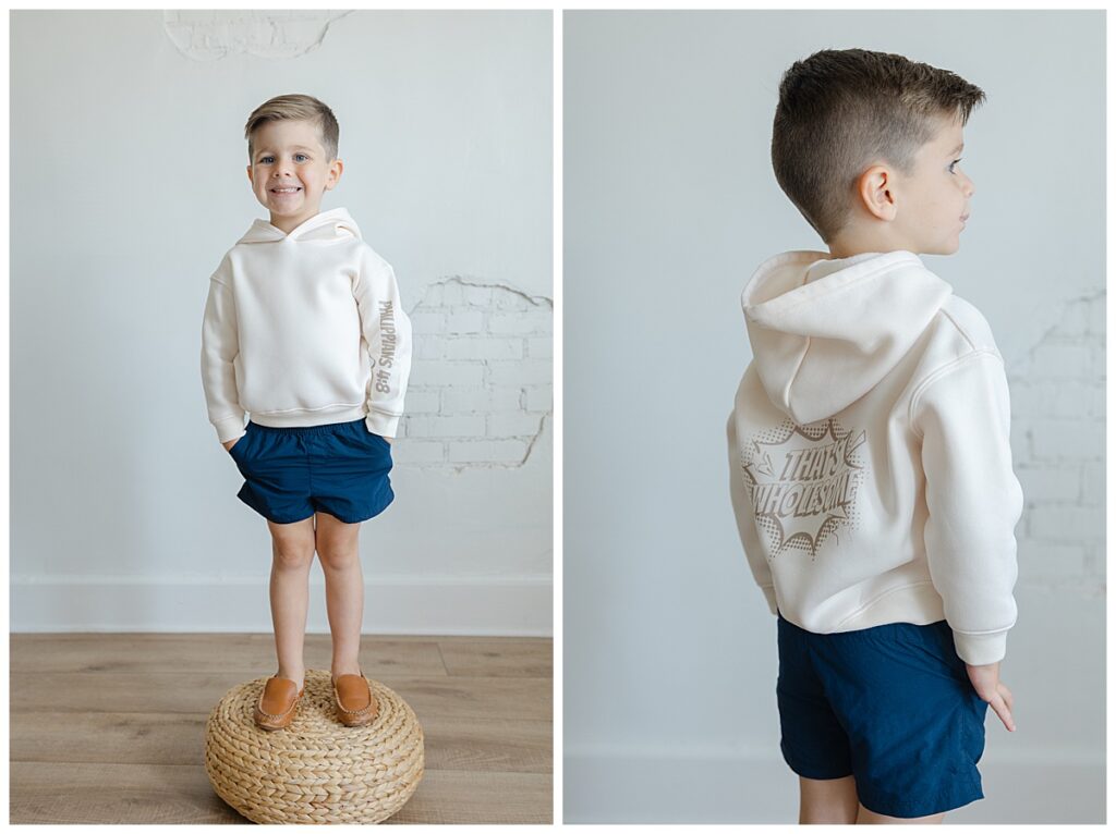 Little boy modeling cream hoodie with Philippians 4:8 design and navy shorts during a studio session by Shreveport brand photographer.