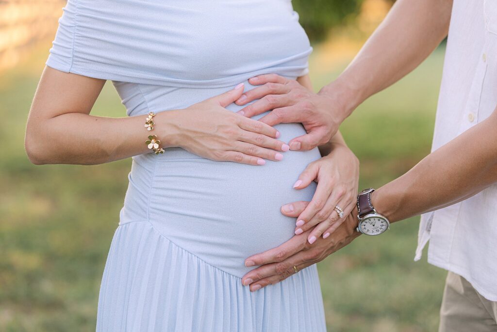 Husband and wife holding pregnant belly.