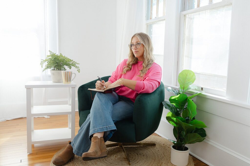 Business woman in pink top and jeans posed in chair