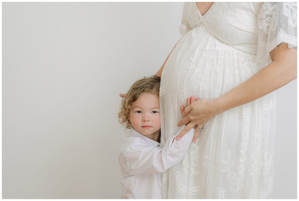 studio maternity session with toddler sibling hugging baby bump during Shreveport maternity family photos